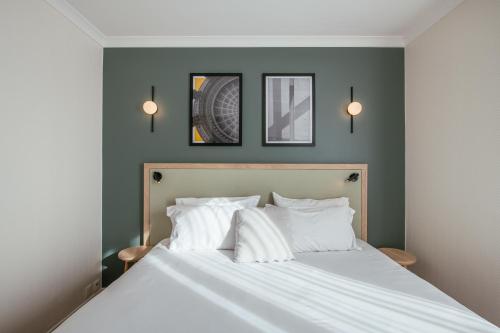 une chambre avec un lit blanc avec trois tableaux au mur dans l'établissement Aparthotel Adagio Paris Buttes Chaumont, à Paris