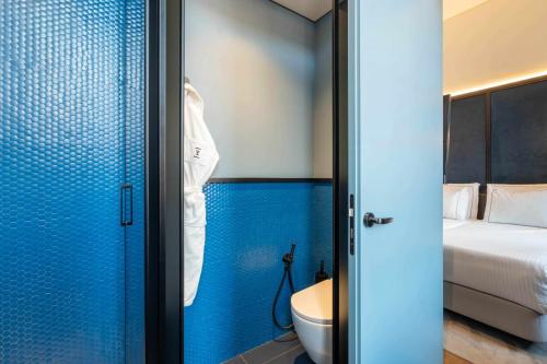 a bathroom with a toilet and a blue wall at The Editory Riverside Hotel, an Historic Hotel in Lisbon