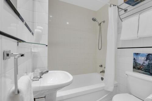 uma casa de banho branca com um lavatório e uma banheira em Liv MTL Avenue em Montreal