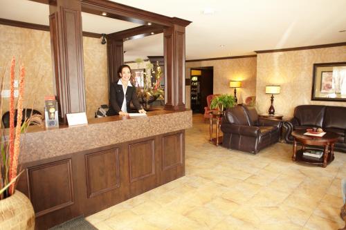 a woman standing at a reception desk in a hotel lobby at Hotel & Suites Monte-Cristo in Quebec City