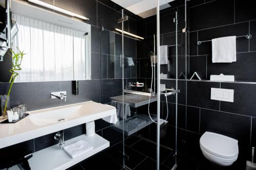 a black bathroom with a sink and a toilet at Mercure Chur City West in Chur