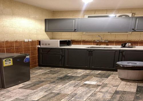 a kitchen with black cabinets and a microwave at SNOW CLOUD in Abha