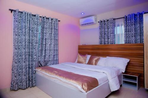 a bedroom with a large bed with blue curtains at Hexagon Hotel in Asi