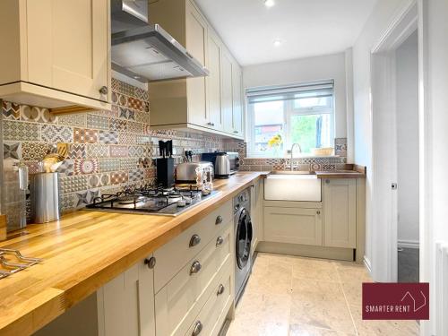 eine Küche mit weißen Schränken und einem Herd mit Backofen in der Unterkunft Farnborough - Newly Refurbished 2 Bedroom Home in Blackwater