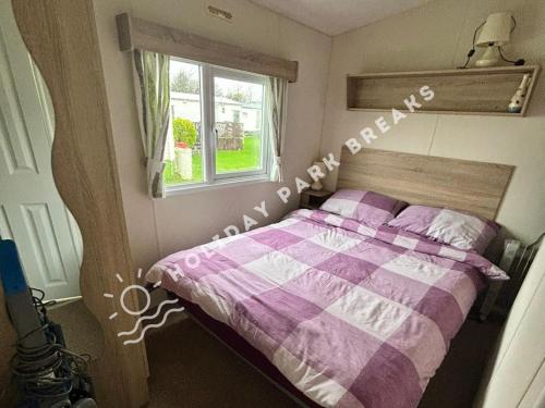 a bedroom with a purple and white bed with a window at Cosy 2 bed @ Seal Bay, Selsey in Selsey