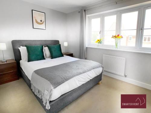 a bedroom with a large bed with green pillows at Wokingham - 2 Bed House with parking and garden in Wokingham