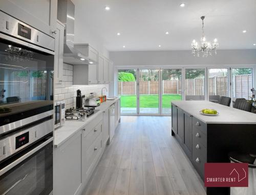 a large kitchen with white cabinets and a large island at Thames Ditton - Luxury 4 Bedroom House - Garden and Parking in Thames Ditton