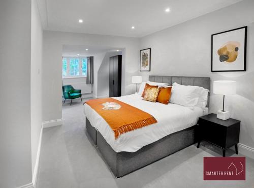 a bedroom with a large bed with an orange blanket at Thames Ditton - Luxury 4 Bedroom House - Garden and Parking in Thames Ditton