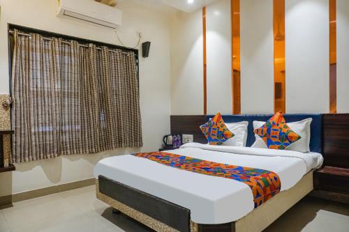 - une chambre avec un grand lit et des oreillers colorés dans l'établissement FabHotel Tulsi Park, à Shirdi