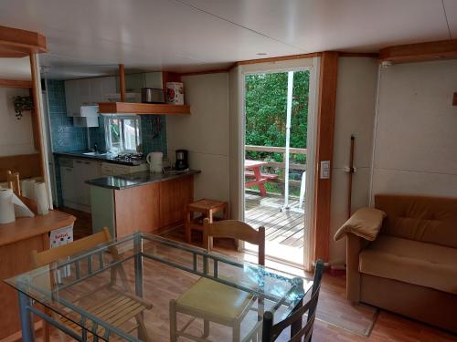 a living room with a glass table and a kitchen at Camping L'Enclave mobil-home in Estavar