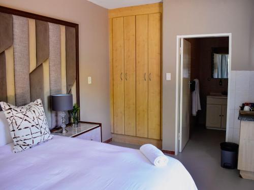 a bedroom with a large white bed and a bathroom at Serene Guest Manor in Johannesburg
