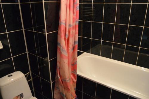 Łazienka z zasłoną prysznicową obok wanny w obiekcie Коломия готель w mieście Kołomyja