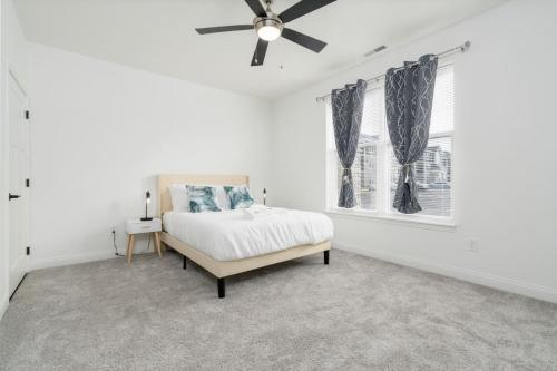 a white bedroom with a bed and a ceiling fan at Corporate Housing by MGM in Whitestown