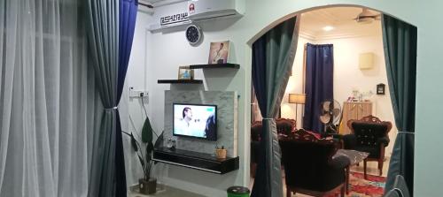 een woonkamer met een tv en een spiegel bij FH Homestay 4BR in Wakaf Baharu