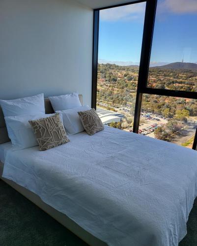 a bed in a room with a large window at 2 Bedroom Apartment on Nightfall in Belconnen