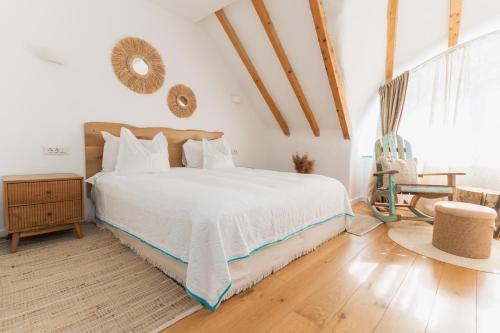 a bedroom with a large white bed and a wooden floor at La Iaz in Murighiol