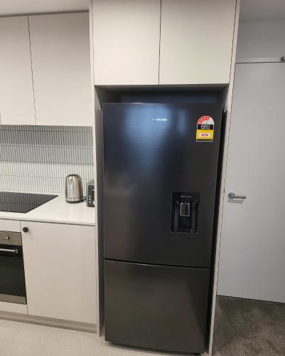 a black refrigerator with a sticker on it in a kitchen at 2 Bedroom Apartment on Nightfall in Belconnen