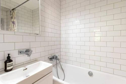 a white bathroom with a tub and a sink at Central London Stylish Flat with Terrace in London