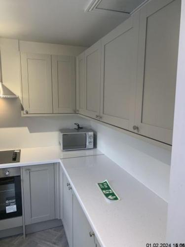 a kitchen with white cabinets and a microwave at Silcoates Houser in Wakefield