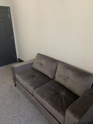 a brown couch in a living room with a door at Silcoates Houser in Wakefield