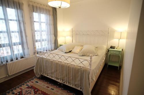 a white bed in a bedroom with two windows at MECİT KAPTAN KONAĞI in Kastamonu