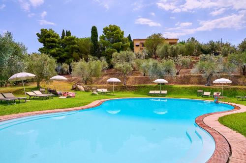 a large swimming pool with chairs and umbrellas at Hotel Z&igrave; Martino in Castagneto Carducci