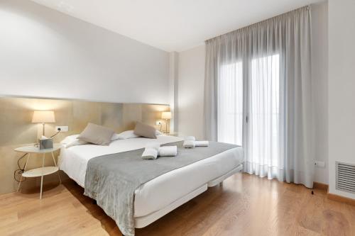 a white bedroom with a large bed and a window at Sensation Authentic Gràcia in Barcelona