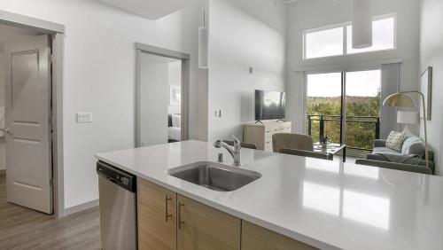 een witte keuken met een wastafel en een woonkamer bij Landing Modern Apartment with Amazing Amenities (ID9335X34) in Kent