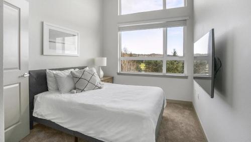 een witte slaapkamer met een bed en 2 ramen bij Landing Modern Apartment with Amazing Amenities (ID9335X34) in Kent