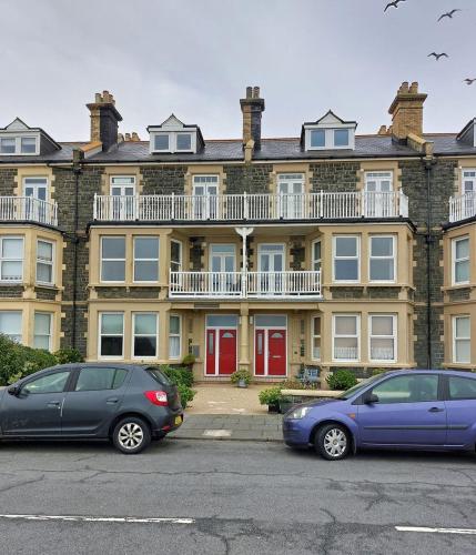 two cars parked in front of a large building at Trem Y Mor - Edge of the Sea in Tywyn