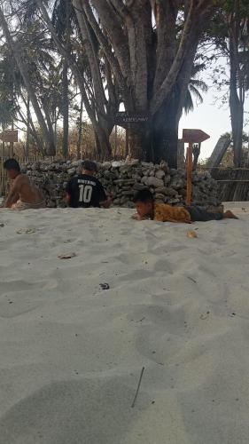 eine Gruppe von Menschen, die auf dem Sand am Strand liegen in der Unterkunft BALE G-SHOQ in Kuta Lombok