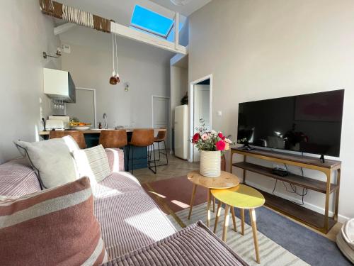 Una sala de estar con un sofá y un televisor. en .Le Perchoir., en Les Sables-dʼOlonne