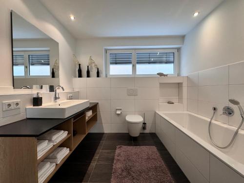 a bathroom with a sink and a tub and a toilet at Ambiente in Überlingen