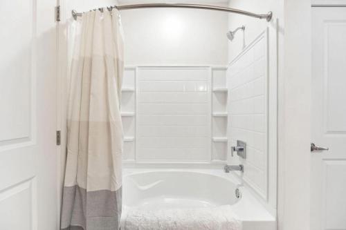 ein weißes Bad mit einem Duschvorhang und einer Badewanne in der Unterkunft Landing Modern Apartment with Amazing Amenities (ID7435X07) in Omaha