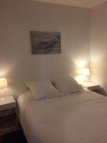 une chambre avec un lit blanc avec deux tables de nuit et deux lampes dans l'établissement Appartement moderne et cosy, à Bonifacio