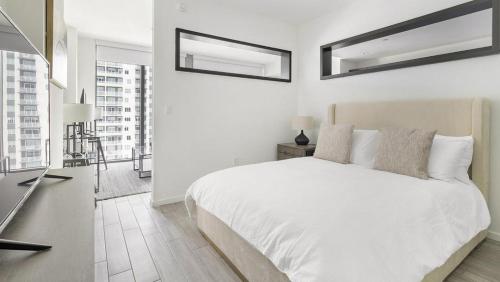 a white bedroom with a white bed and two mirrors at Landing Modern Apartment with Amazing Amenities (ID1283X920) in Fort Lauderdale