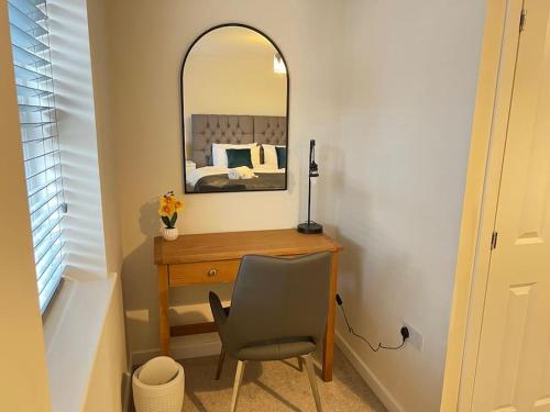 Schlafzimmer mit einem Schreibtisch, einem Spiegel und einem Stuhl in der Unterkunft Braid House in Loughborough