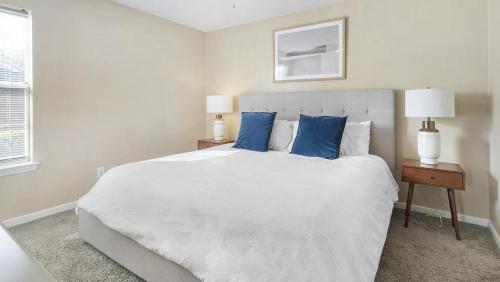 - une chambre blanche avec un grand lit blanc et des oreillers bleus dans l'établissement Landing Modern Apartment with Amazing Amenities (ID1402X064), à Slidell