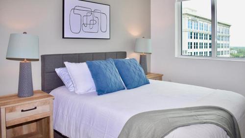 um quarto com uma cama com almofadas azuis e uma janela em Landing Modern Apartment with Amazing Amenities (ID2665X75) em Fort Lauderdale