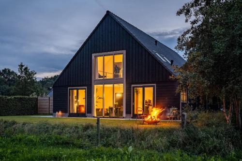 a black house with a fire in front of it at Het Landzicht in Houtigehage