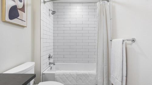 uma casa de banho com uma banheira branca e um WC. em Landing Modern Apartment with Amazing Amenities (ID8566X33) em Vancouver