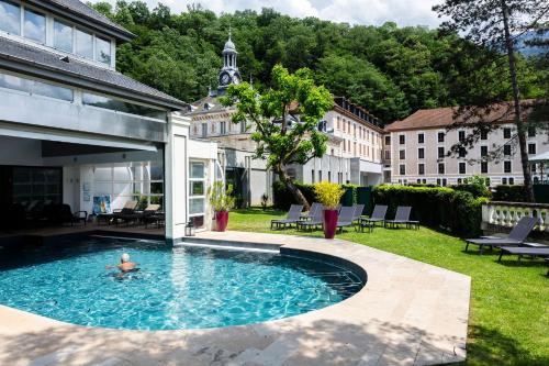 a person swimming in a swimming pool in a yard at Grand Hôtel & Spa Uriage in Uriage-les-Bains