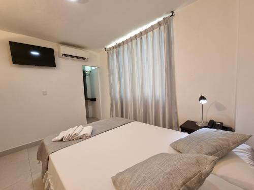 a bedroom with two beds and a television on the wall at K12 Hotel in Barrancabermeja