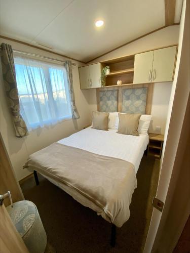 um quarto com uma grande cama branca e uma janela em Downtime, West Sands, Seal Bay Resort, Selsey em Selsey