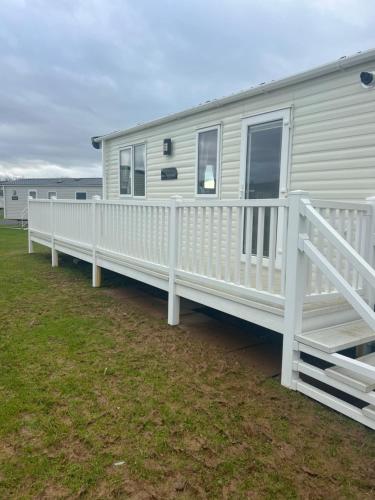 a mobile home with a white porch and fence at GDs Luxury Caravan Hire Turnberry Holiday Park in Turnberry