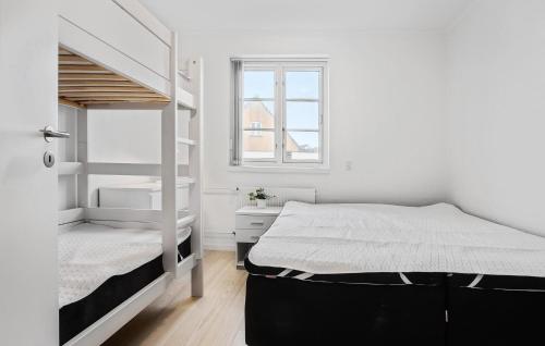 a white bedroom with a bunk bed and a window at Amazing Home In Blokhus With Kitchen in Blokhus