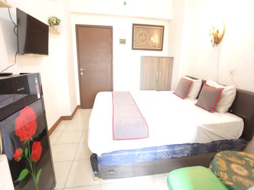 a bedroom with a bed and a flat screen tv at Aurora Rooms @ Apartemen Loftvilles City in Dukuh
