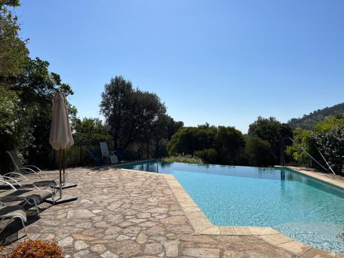 une piscine avec des chaises et un parasol dans l'établissement La Villa des Pins à Benat, à Bormes-les-Mimosas