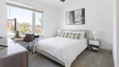 een witte slaapkamer met een bed, een bureau en een raam bij Landing Modern Apartment with Amazing Amenities (ID1791X17) in Richmond