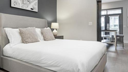 Landing Modern Apartment with Amazing Amenities (ID1208X667) في ديكاتور: غرفة نوم بسرير ابيض كبير وطاولة